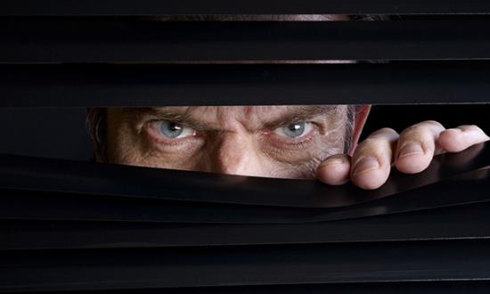  paranoid man peers through window blinds